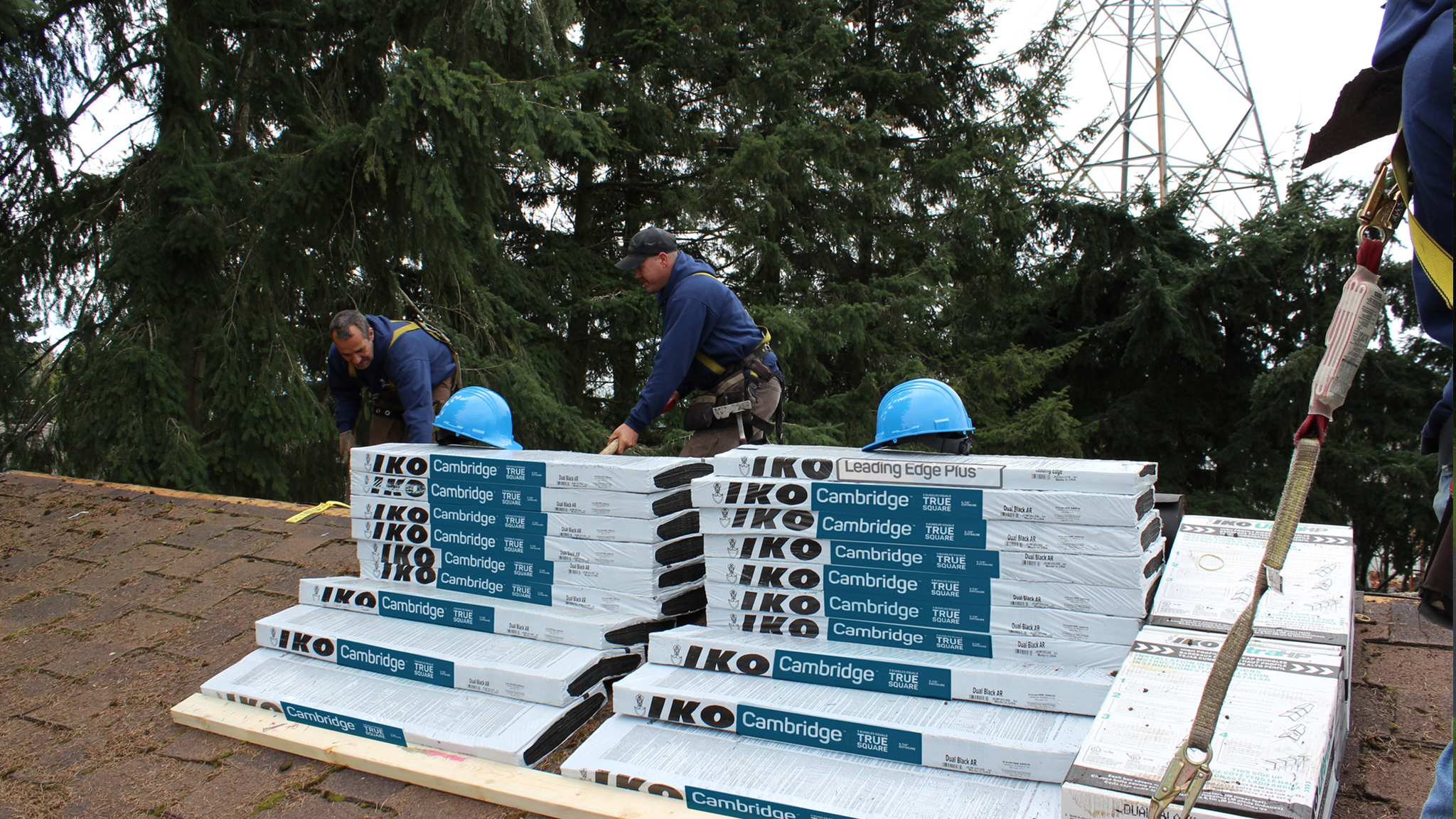 Roofing crew staging materials at the base of a house